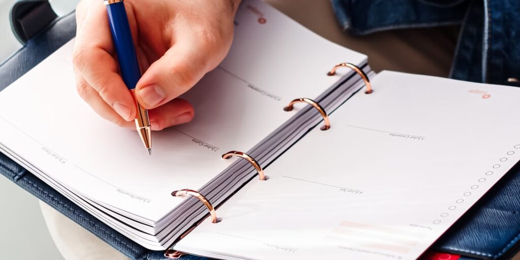 Hand die met een pen aantekeningen maakt in een planner