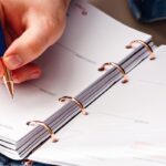 Hand die met een pen aantekeningen maakt in een planner